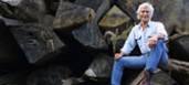 Arky sitting by salvaged redwood logs